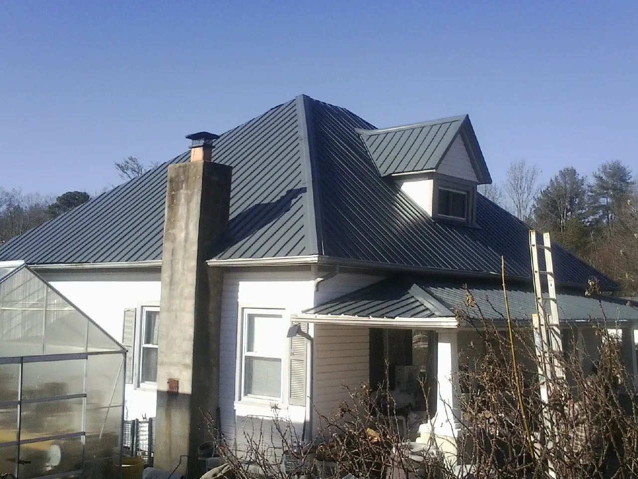 Dark blue standing seam metal roof on a white farmhouse with dormer — Slate & Tile Roof Repair by Roofing Brothers in South Plainfield