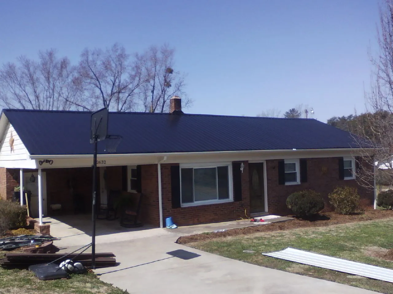 Finished dark blue metal roof on a brick ranch with a carport in South Plainfield