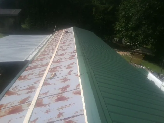 Old rusted panels beside newly installed green metal roofing — Wind Damage Roof Repair by Roofing Brothers in South Plainfield