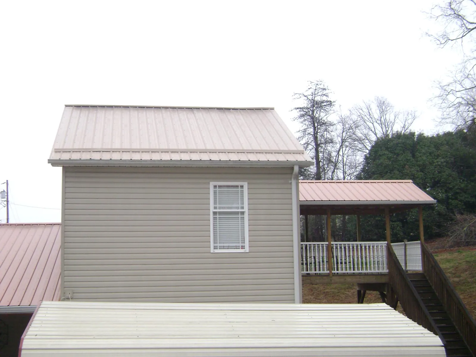 Tan metal roofs on a two story addition and attached porch, from a Roof Replacement job in South Plainfield